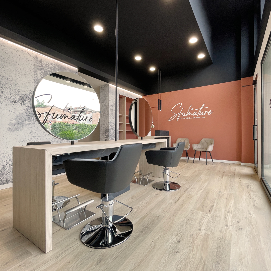 Immagine dell'area stilistica con pareti color mattone, poltrone nere e specchi. Mobili in legno 